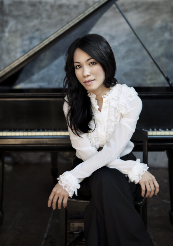 Qynh Nguyen sitting in front of piano